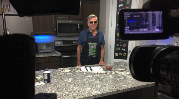 Tommy stands in the kitchen with knives and a cutting board on the counter in front of him